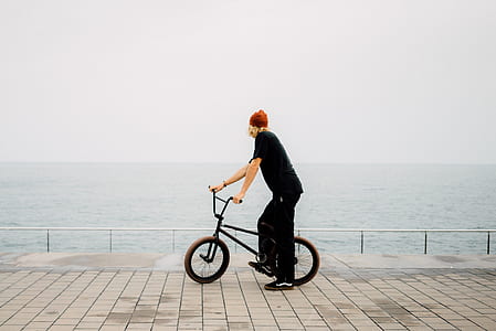 man looking at sea while holding bicycle thumbnail