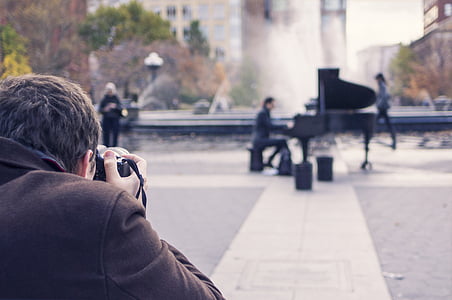 man taking photo of man playing piano near fountain at daytime thumbnail