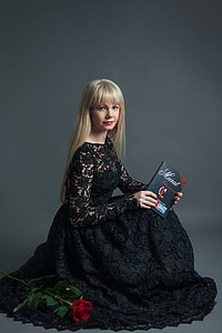 woman wearing black lace dress holding book looking on camera thumbnail