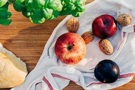 two red apples beside brown nuts on white handkercheif thumbnail