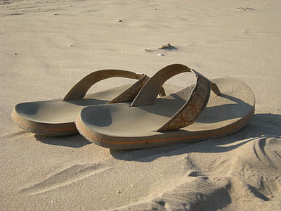 pair of brown flip-flops on sand thumbnail