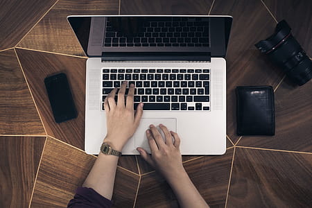 person using silver MacBook on brown surface thumbnail