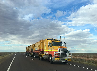 yellow and orange semi trailer truck on highway thumbnail