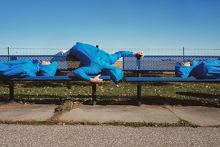 photo of three person wearing blue hoodies laying in blue metal bench thumbnail