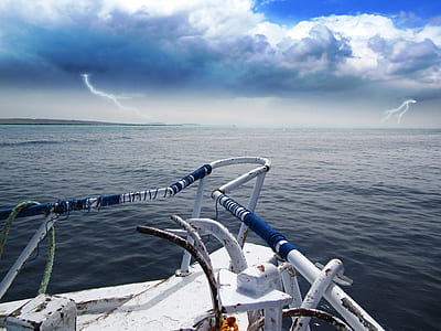 white boat on body of water near lightning strikes thumbnail