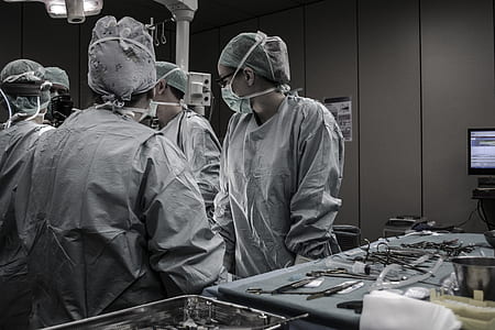 five people wearing masks standing beside tools inside medical room thumbnail