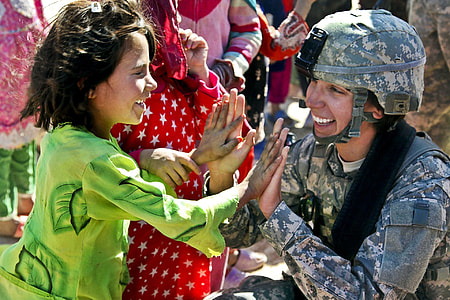 woman in green long sleeved top in front of woman in gray and beige army uniform thumbnail
