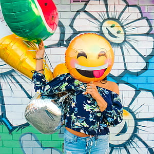 woman holding inflatable balloon against graffiti wall thumbnail