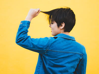 woman wearing blue denim jacket near yellow wall thumbnail