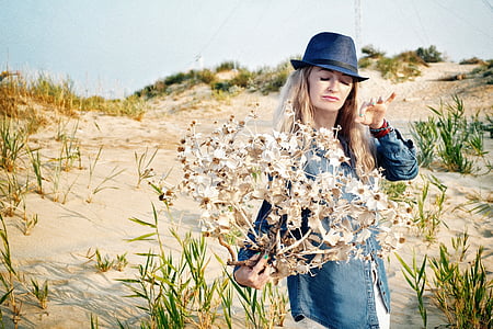 woman wearing blue chambray jacket holding white flower during daytime thumbnail