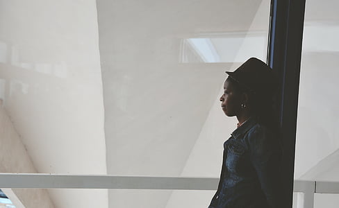 woman wearing cap standing beside glass panel wall thumbnail