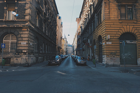 gray concrete road between parked cars during daytime thumbnail