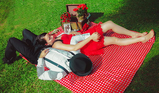 man and woman leaning on red and white plaid picnic mat thumbnail