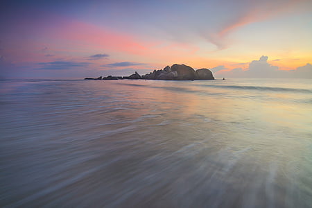 brown islet on ocean during golden hour thumbnail