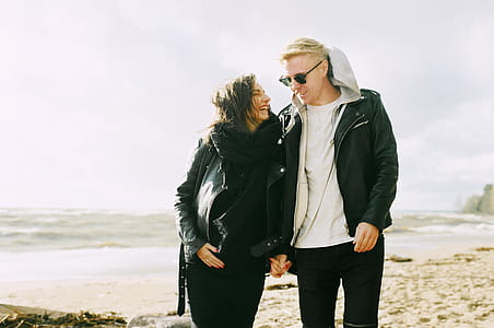 Man and Woman Wearing Jackets Near Seaside Under Cloudy Sky thumbnail