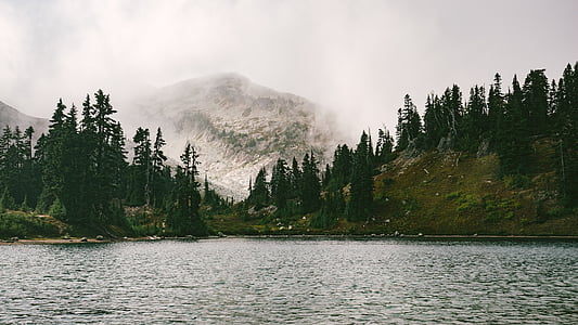 body of water near mountain with trees thumbnail