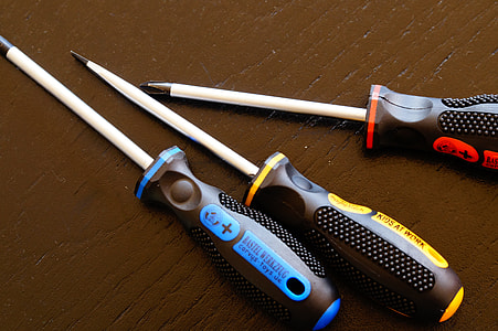 three assorted-color screw drivers on brown surface thumbnail