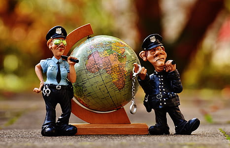 tilt shift lens photo of two policemen figurines beside globe thumbnail
