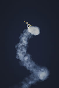 timelapse photography of biplane gliding with smoke in the sky thumbnail