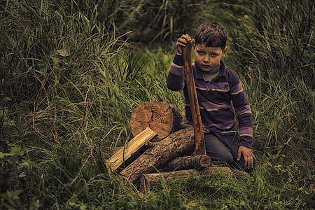 boy wearing a purple and black polo shirt while holding a brown wood thumbnail