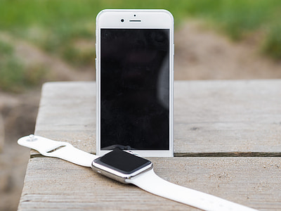 silver aluminum Apple Watch beside silver iPhone 6 on table outdoors during day thumbnail