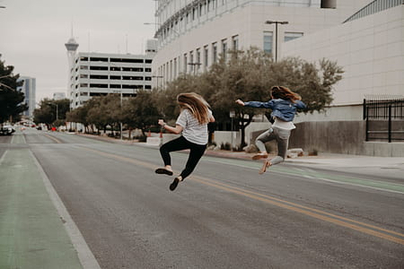 two women jumping on road thumbnail