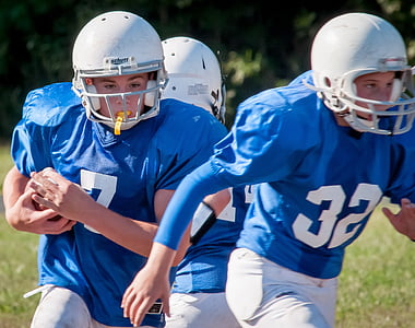 three American football players playing on field during daytime thumbnail