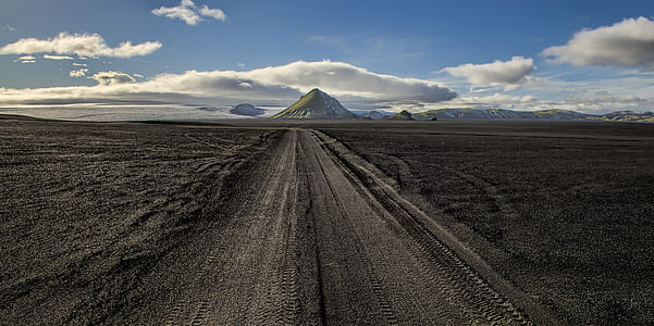 wide angle photo of brown road under cloudy sky thumbnail