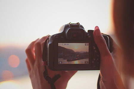 person holding a DSLR camera while taking a photo of an island thumbnail