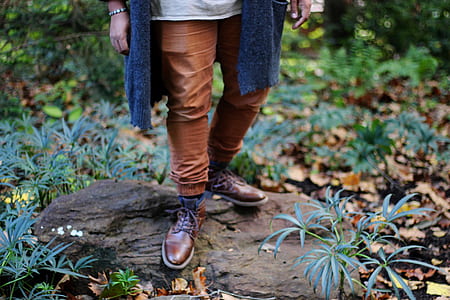 person standing on brown stone surrounded by grass thumbnail