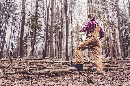 person wearing brown denim overalls standing under trees during daytime thumbnail
