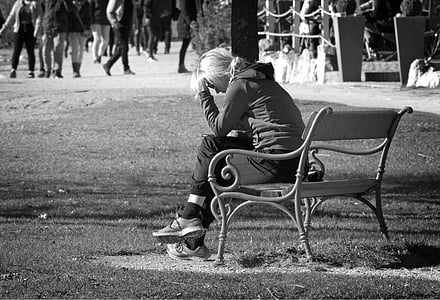 grayscale photography of woman sitting on bench while resting her hand on head thumbnail