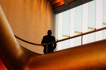 man wearing black long-sleeved shirt standing in front of glass window near grey stainless steel handrails thumbnail