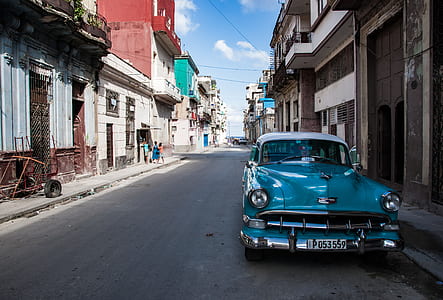 blue classic vehicle on road between houses thumbnail