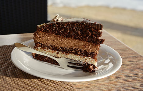 slice of cake on round white ceramic saucer on brown wooden surface thumbnail