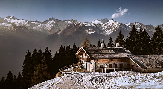 white and black house surrounded by green leafed trees and mountains during daytime thumbnail