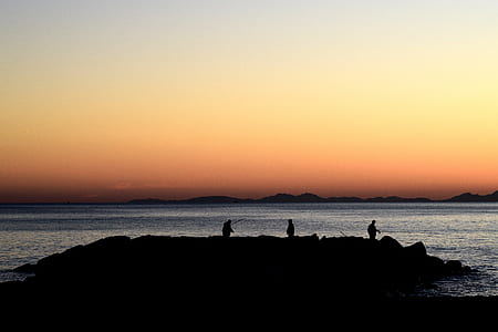 silhouette photo of three people on island thumbnail