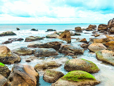 Landscape Photography of Rocks With Moss Surrounded by Body of Water thumbnail