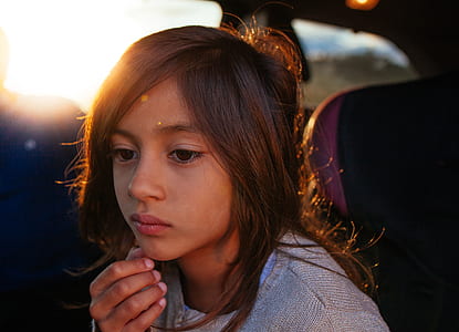 girl sitting on vehicle seat holding her chin during during golden hour thumbnail