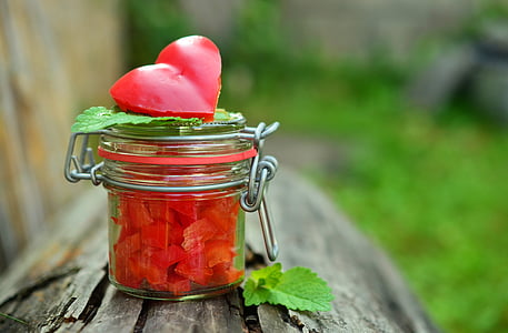 red fruit inside clear glass jar on brown log thumbnail
