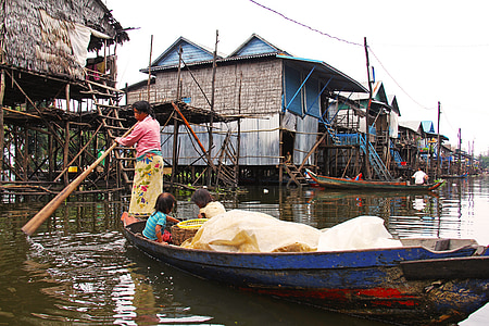 woman and two child on canoe near brown houses thumbnail