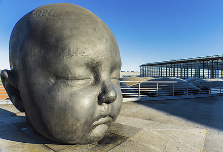 baby's face statue on pavement near handrails at daytime thumbnail