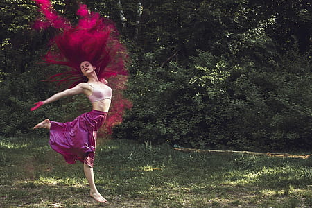 purple haired woman in pink sleeveless crop top jumping on green grass field thumbnail
