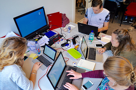 group of four people gathered on a table using laptops thumbnail