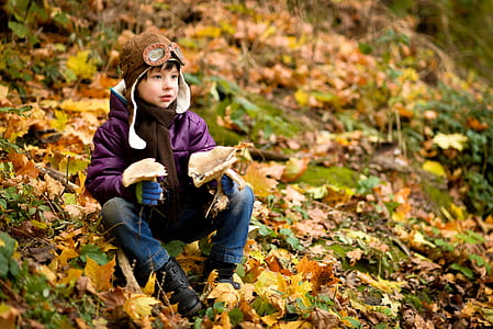 boy sitting on ground covered with leaves thumbnail