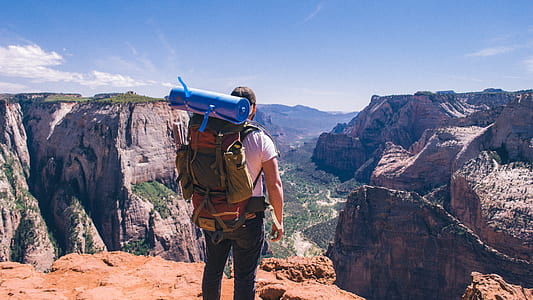 man standing on cliff wearing trek backpack thumbnail