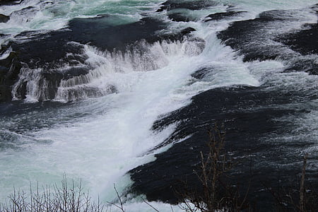 water gushing from rocks at daytime thumbnail