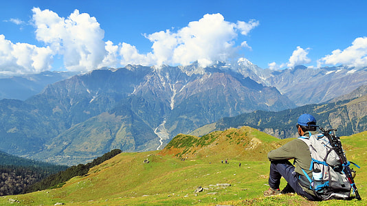 man sitting on green lawn looking at the mountain at daytime thumbnail