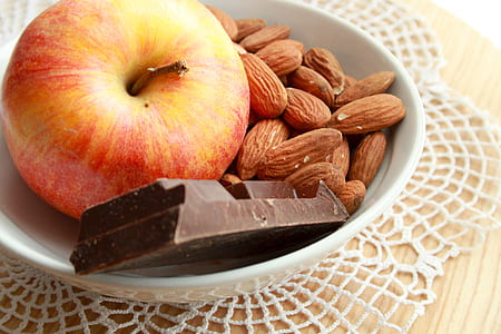 apple, chocolate, and almonds in white ceramic bowl thumbnail