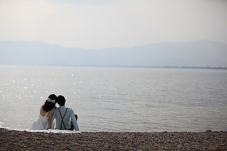 couple sitting on seashore during daytime thumbnail